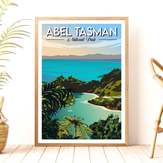 A framed travel poster depicting Abel Tasman National Park with a scenic view of a beach and forested hills, titled 'ABEL TASMAN National Park', with a plant and a bamboo stick at the sides.