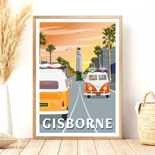 A framed travel poster depicting Gisborne, New Zealand at sunrise with iconic surf vans and a clock tower, displayed in a home setting.