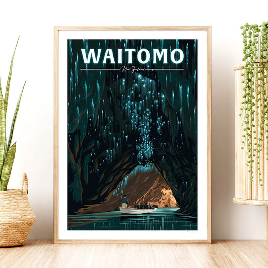 A framed travel poster depicting the Waitomo Caves with glowworms, limestone formations, and a boat in a Underground River. The poster is displayed in a room setting with a plant to the side.